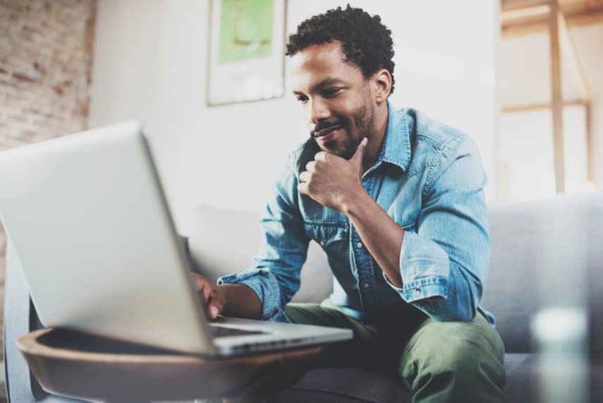 Man sitting on couch running a Facebook ads business from home 